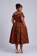 Back view of  woman modeling an off-the-shoulder Ankara midi dress with a vibrant orange, brown, and green geometric pattern