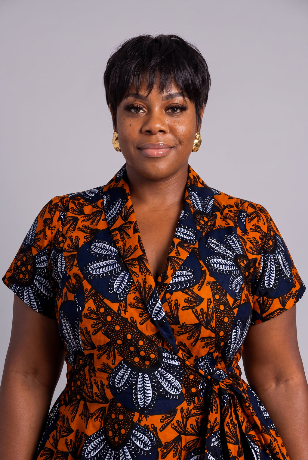 Plus size model wearing a vibrant orange and navy blue patterned Ankara wrap dress 