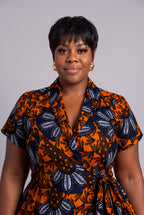 Plus size model wearing a vibrant orange and navy blue patterned Ankara wrap dress 