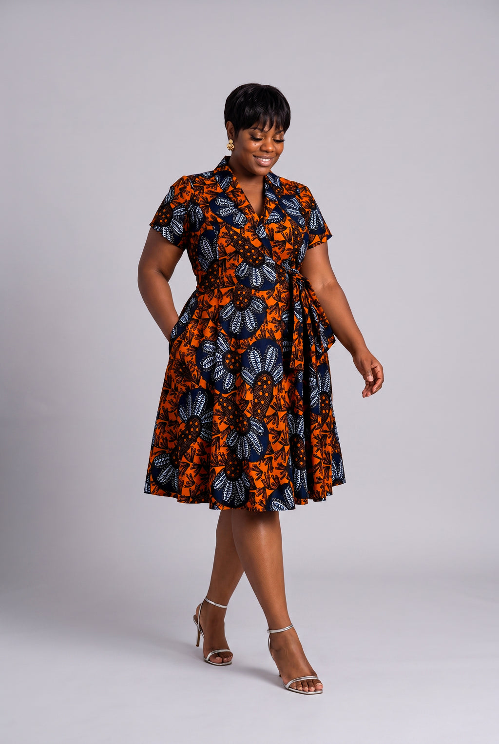 Model walking in fit and flare African print wrap dress 