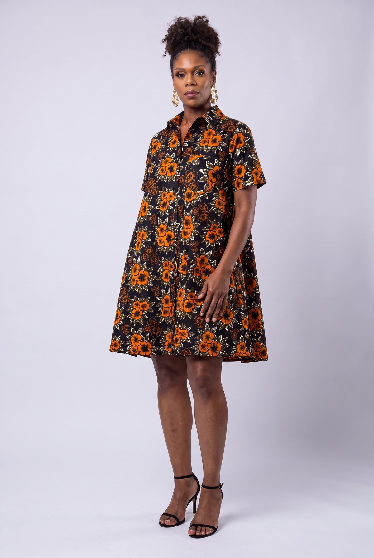 Model wearing Amber Bloom orange African print swing shirt dress with short sleeves and a relaxed fit