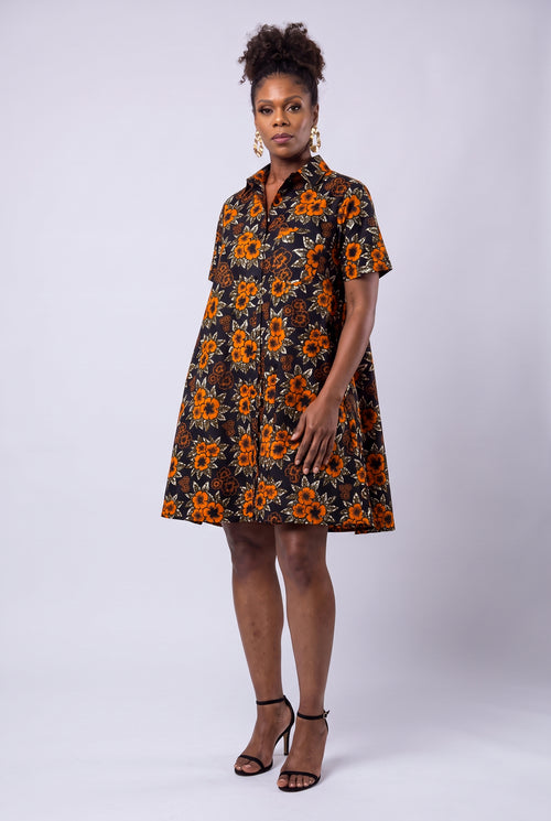 Model wearing Amber Bloom orange African print swing shirt dress with short sleeves and a relaxed fit