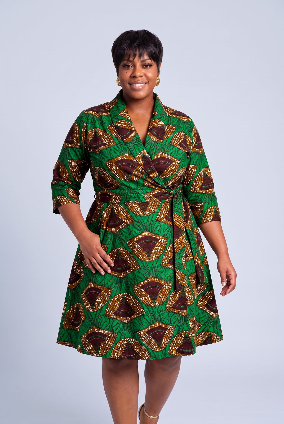 Model walking in Forest Oasis green and gold Ankara wrap dress with flowing midi skirt