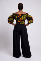 Back view of Olive Oasis orange and green African print wrap top worn with black palazzo trousers