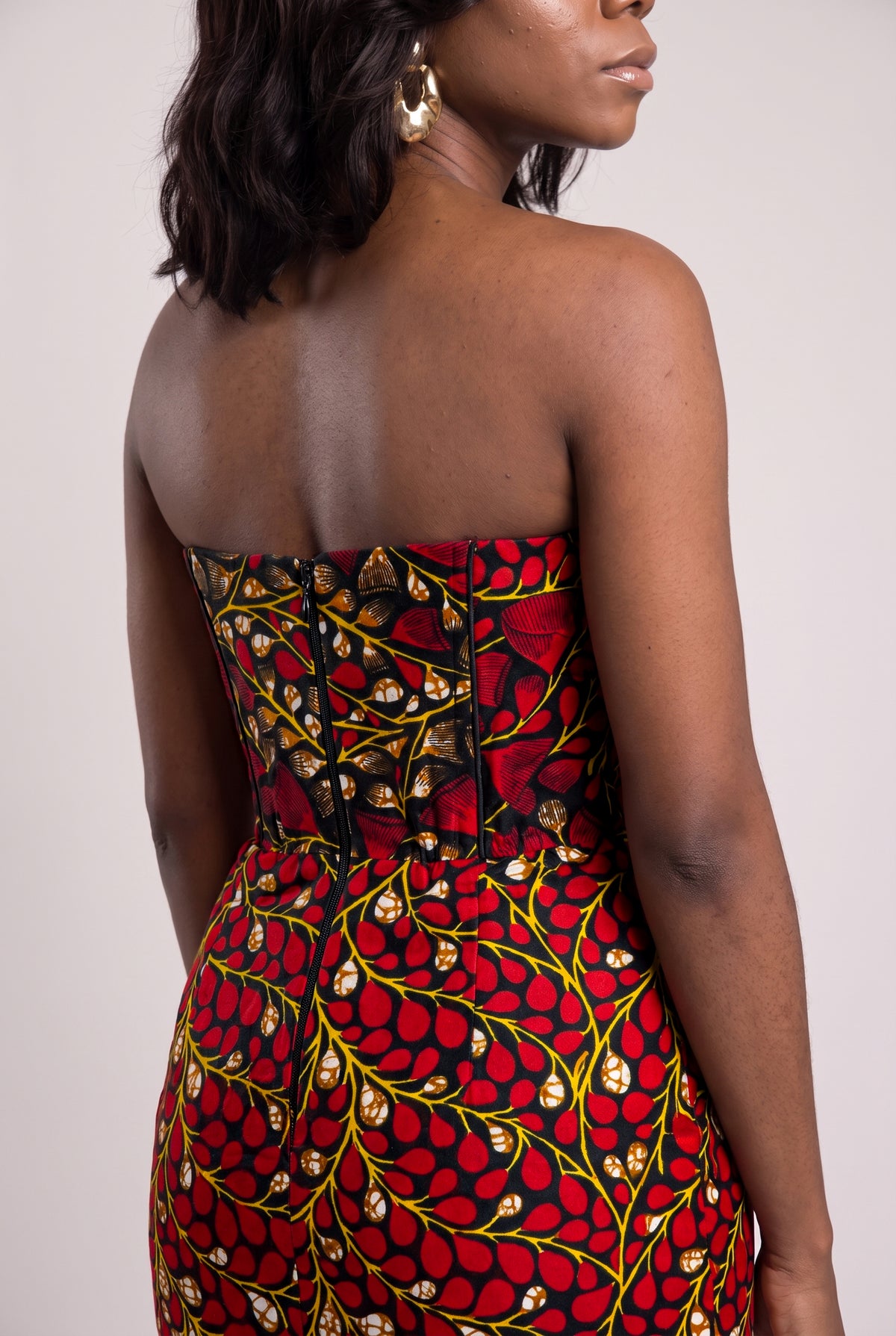 Close up back view of structured African wax print dress with leaf pattern in vibrant red and black