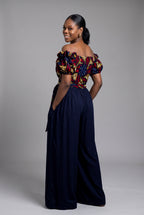 Back view of a tailored off shoulder wrap Ankara top in vibrant red and navy blue wax print and Navy Trouser 