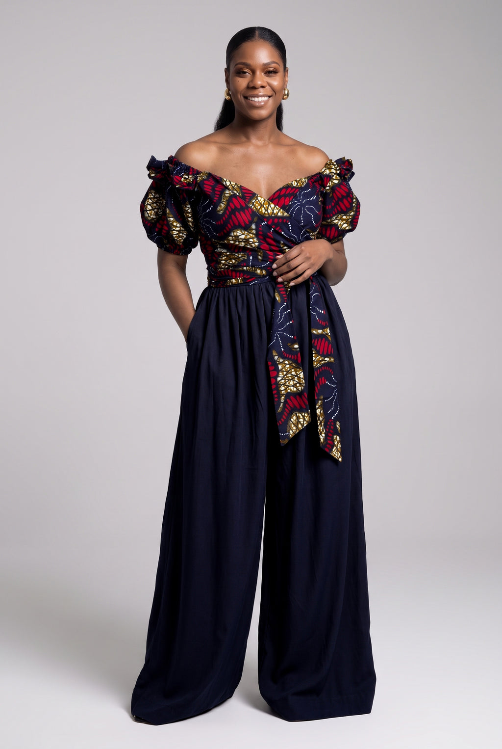 A woman styling an off-shoulder crossover Ankara blouse with high-waisted navy Palazzo trousers