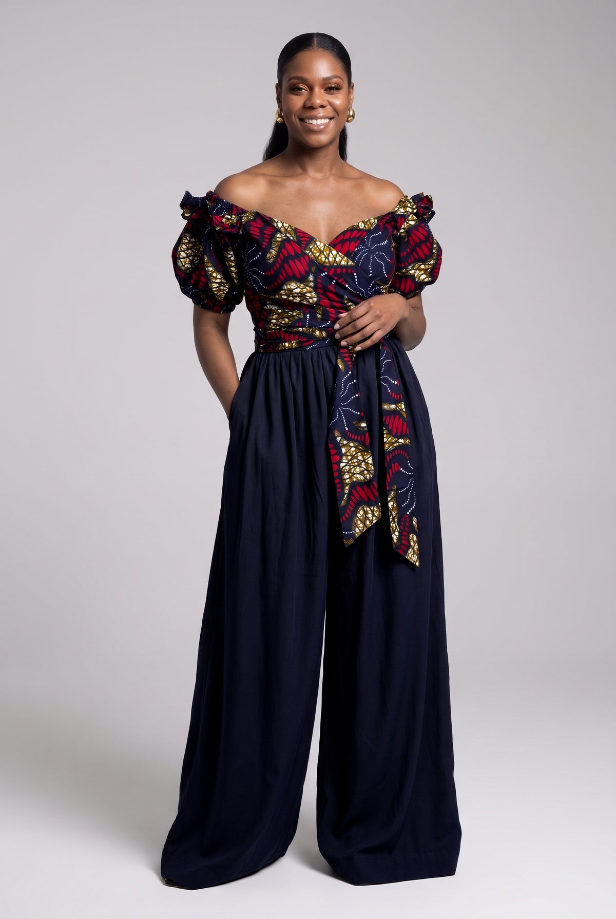 A woman styling an off-shoulder crossover Ankara blouse with high-waisted navy Palazzo trousers