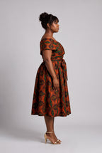 Side profile view of a curvy model wearing orange African print dress